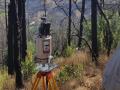 a measuring device stands on a hill amongst charred trees