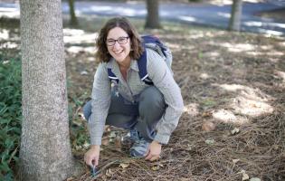 Dr. Lisa Bentley smiling and crouching by a tree