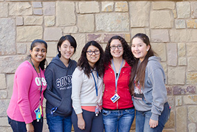 A group of female students standing in front of a rock wall